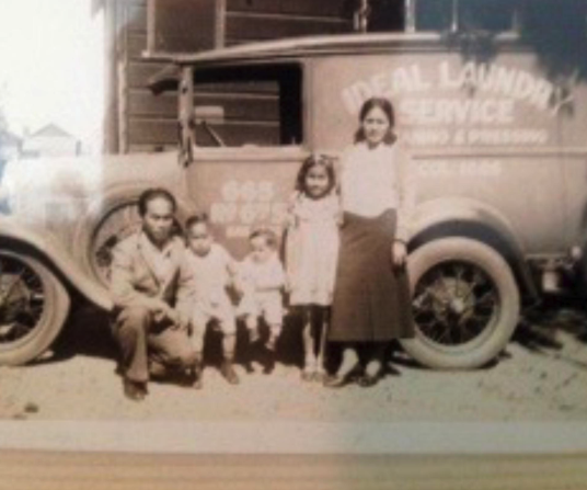 A black and white photo of a family standing in front of a truck that says "Ideal Laundry"