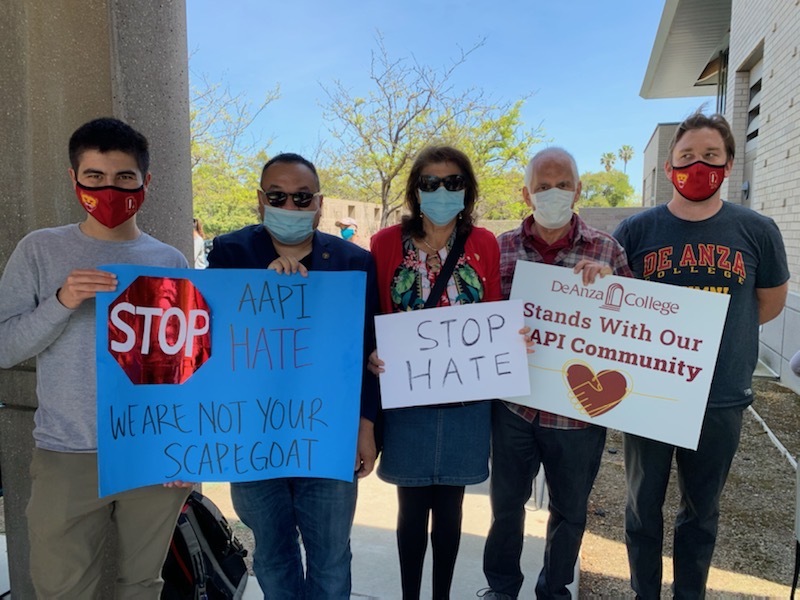 Five people standing with signs against racism