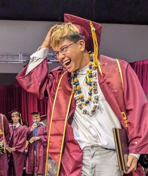 student smiling with hand on grad cap