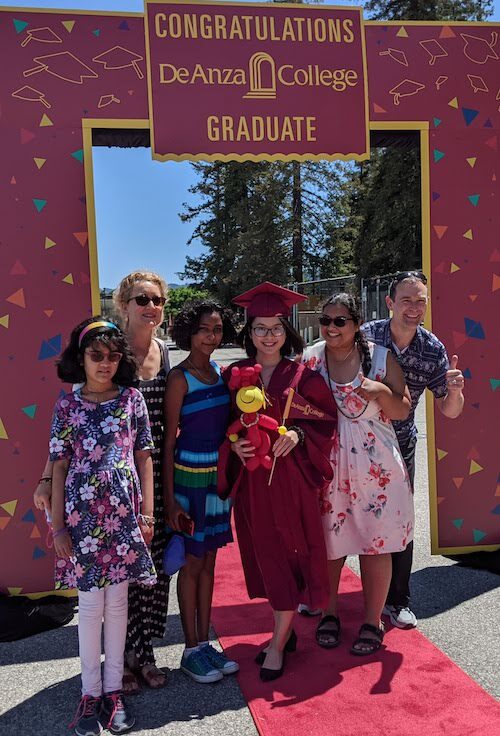 student in grad regalia with family members standing together